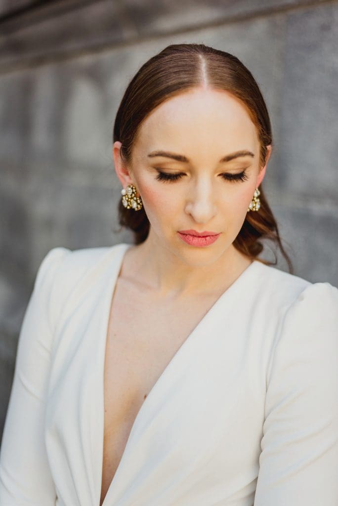 Bride in a white wedding dress looking down.