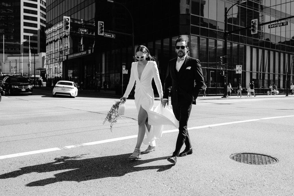 Candid black and white shot of the couple walking together down the street, hand in hand.
