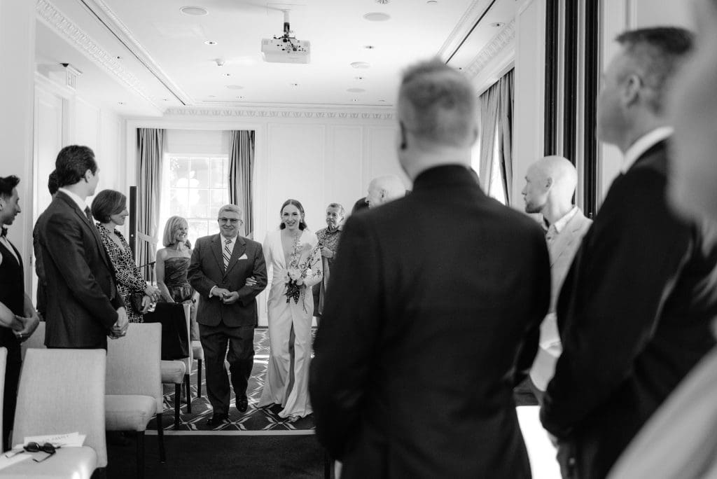 Black and white photo of the bride walking down the aisle with her father