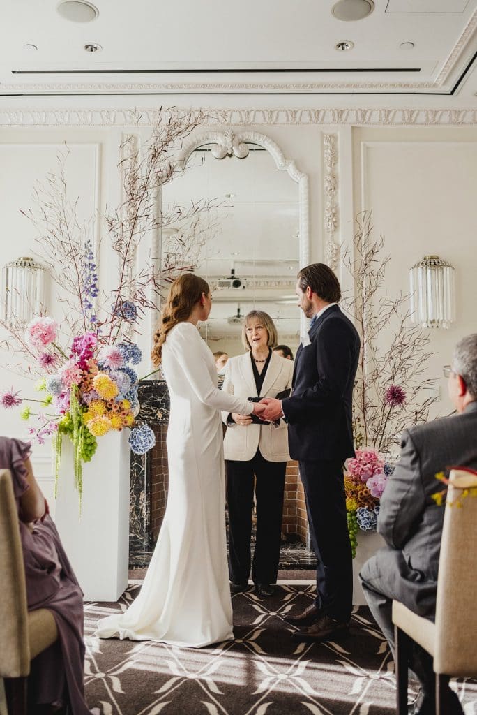Bride and groom at the altar, attentively facing the judge as they begin their vows.