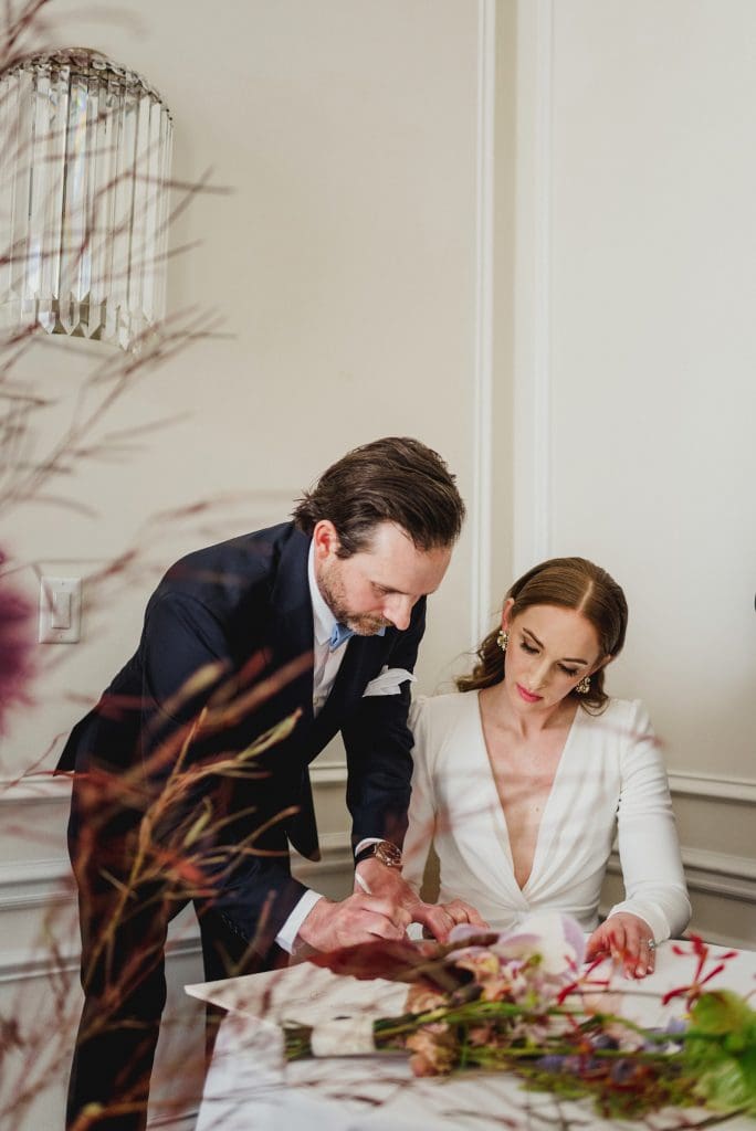 Intimate moment of the couple signing their marriage certificate, sealing their union.