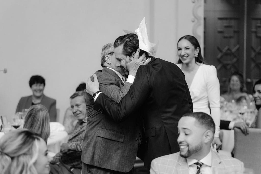 Heartfelt moment as the father of the bride embraces the groom, sharing words of love and wisdom.